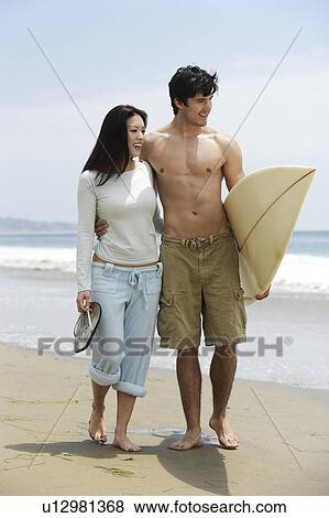 Young couple with surfboard on beach View Large Photo Image Stock Photo - Young couple with surfboard on beach. Fotosearch