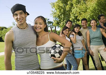 Young couple with woman holding soccer ball, group of friends in background. View Large Photo Image Stock Photography - Young couple with woman holding soccer ball, group of friends in background.. Fotosearch