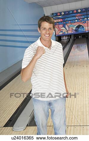 Stock Photography - Young man at bowling alley celebrating, portrait. Fotosearch