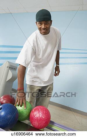 Young man at bowling alley choosing ball, portrait View Large Photo Image Picture - Young man at bowling alley choosing ball, portrait. Fotosearch