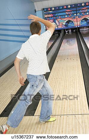 Stock Photo - Young man bowling, back view. Fotosearch