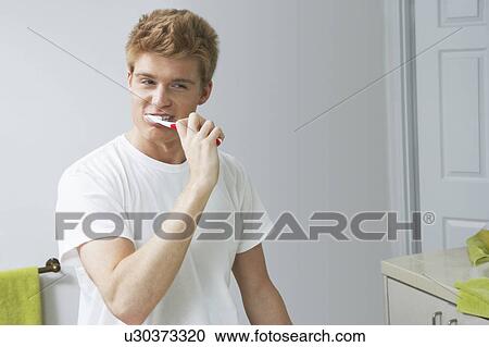 Young man brushing teeth in bathroom View Large Photo Image Stock Image - Young man brushing teeth in bathroom. Fotosearch