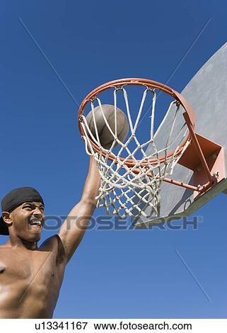 Young man dunking basketball into hoop View Large Photo Image Stock Photo - Young man dunking basketball into hoop. Fotosearch
