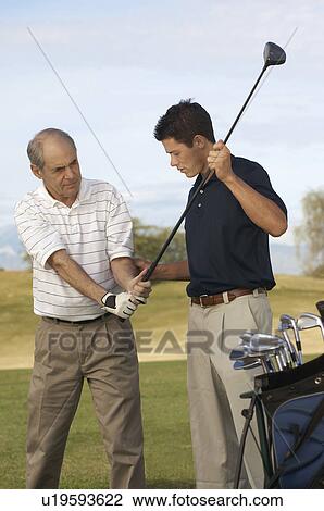 Young Man Helping Man with Grip on Golf Club on golf course View Large Photo Image Stock Image - Young Man Helping Man with Grip on Golf Club on golf course. Fotosearch