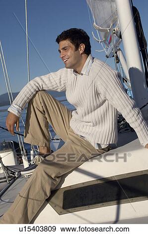 Stock Photo - Young man relaxing on sailboat. Fotosearch