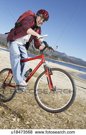 Young Man riding mountain bike on lake shore View Large Photo Image Stock Photo - Young Man riding mountain bike on lake shore. Fotosearch