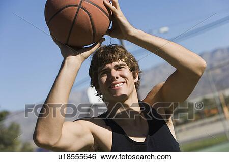 Stock Photograph - Young man shooting basketball, portrait. Fotosearch