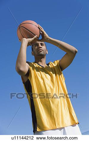 Young man shooting basketball, portrait, low angle view View Large Photo Image Stock Image - Young man shooting basketball, portrait, low angle view. Fotosearch