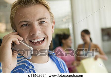 Picture - Young Man Using Cell Phone in clothing Store, portrait, close up. Fotosearch
