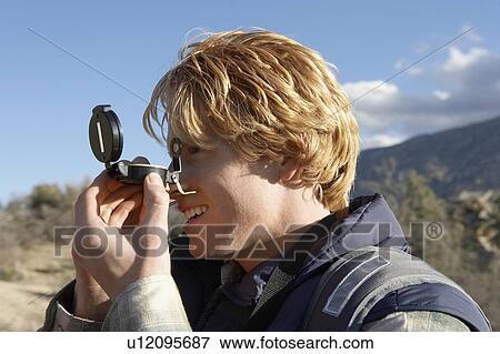 Stock Photo - Young Man using compass, side view.. Fotosearch