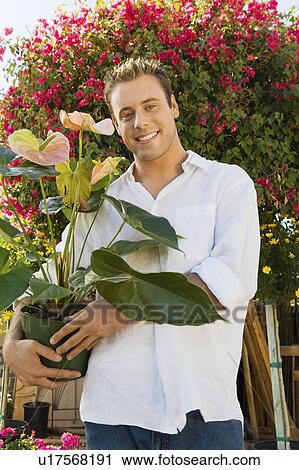 Young man with pushcart in garden centre, (portrait) View Large Photo Image Stock Image - Young man with pushcart in garden centre, (portrait). Fotosearch