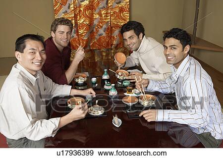Young men eating sushi with chopsticks in restaurant View Large Photo Image Stock Photo - Young men eating sushi with chopsticks in restaurant. Fotosearch
