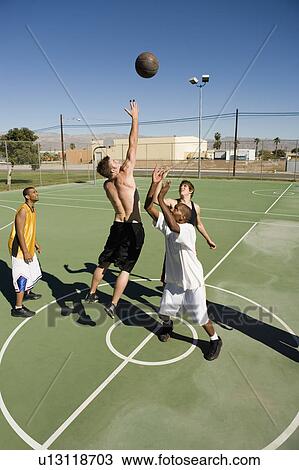 Young men reaching in air for basketball during game View Large Photo Image Stock Image - Young men reaching in air for basketball during game. Fotosearch