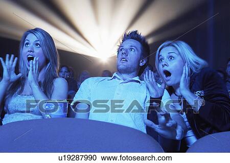 Stock Image - Young People screaming, watching Horror Movie in Theatre. Fotosearch