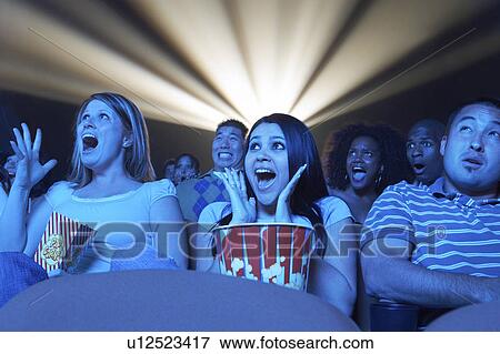 Stock Photo - Young People screaming, watching Horror Movie in Theatre. Fotosearch