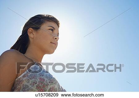 Young woman against clear blue sky, close-up View Large Photo Image Stock Photo - Young woman against clear blue sky, close-up. Fotosearch