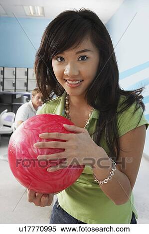 Young woman at bowling alley holding ball, portrait View Large Photo Image Stock Photography - Young woman at bowling alley holding ball, portrait. Fotosearch