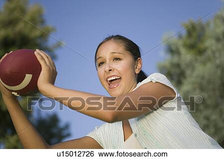 Stock Photograph - Young Woman Holding Football outdoors.. Fotosearch