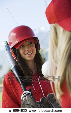 Young woman holding softball bat talking to teammate View Large Photo Image Stock Image - Young woman holding softball bat talking to teammate. Fotosearch