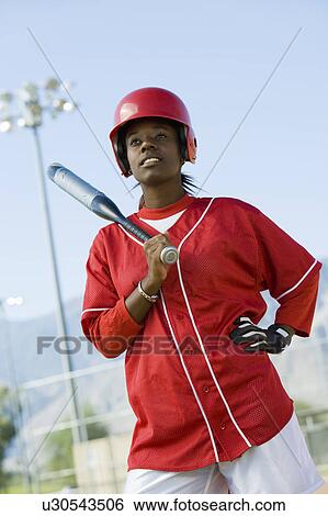 Stock Photograph - Young woman holding softball bat, portrait. Fotosearch
