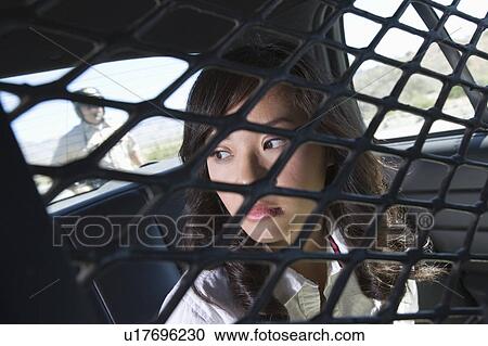 Stock Image - Young woman in back of police car. Fotosearch