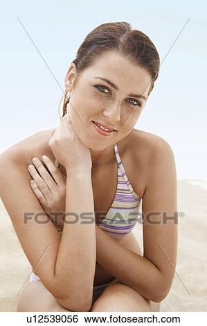 Young woman in bikini sitting on beach, portrait View Large Photo Image Stock Photograph - Young woman in bikini sitting on beach, portrait. Fotosearch