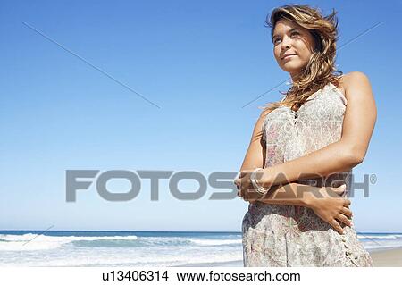 Young woman in summer dress standing on beach View Large Photo Image Picture - Young woman in summer dress standing on beach. Fotosearch