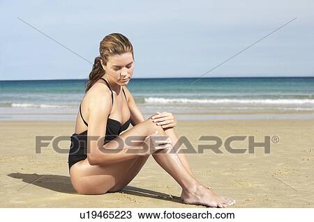 Young woman in swimsuit sitting on beach View Large Photo Image Stock Image - Young woman in swimsuit sitting on beach. Fotosearch
