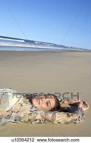 Stock Image - Young woman lying on beach, head and shoulders. Fotosearch
