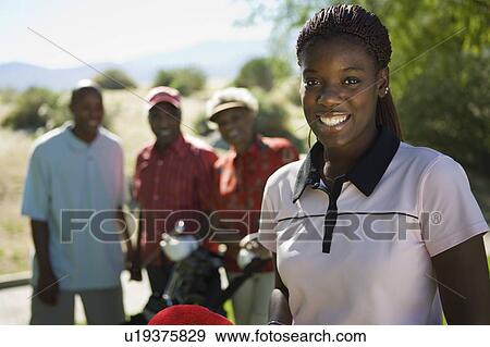 Stock Photo - Young woman on golf course, (portrait), family in background. Fotosearch