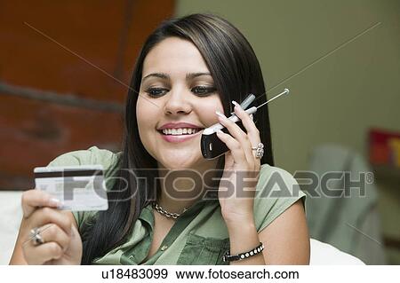 Young woman on sofa making purchase with credit card on mobile phone View Large Photo Image Stock Photo - Young woman on sofa making purchase with credit card on mobile phone. Fotosearch