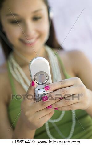 Stock Photo - Young woman on sofa sending text message, focus on mobile phone. Fotosearch