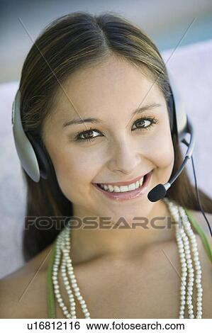 Young woman on sofa wearing phone headset, portrait View Large Photo Image Stock Photograph - Young woman on sofa wearing phone headset, portrait. Fotosearch