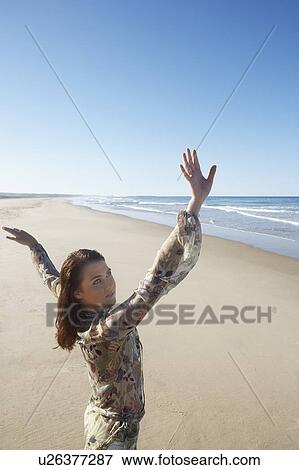 Young woman posing on beach, arms raised View Large Photo Image Stock Photo - Young woman posing on beach, arms raised. Fotosearch