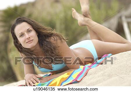 Young Woman Relaxing on Beach, lying down, portrait, tilt view View Large Photo Image Stock Photography - Young Woman Relaxing on Beach, lying down, portrait, tilt view. Fotosearch