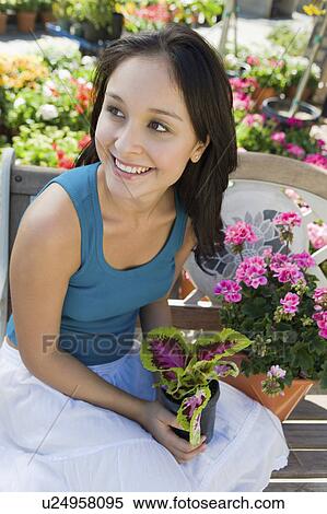 Young woman resting on bench in garden centre, (elevated view) View Large Photo Image Stock Photography - Young woman resting on bench in garden centre, (elevated view). Fotosearch