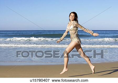 Young woman running on beach, side view View Large Photo Image Stock Photo - Young woman running on beach, side view. Fotosearch