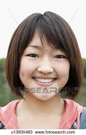 Stock Image - Young woman smiling outside, close-up, portrait. Fotosearch