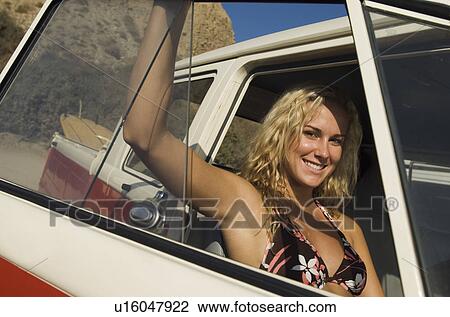 Stock Image - Young woman smiling, sitting in passenger seat of truck. Fotosearch