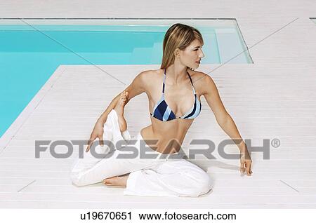 Young woman stretching legs by swimming pool, front view, full length View Large Photo Image Stock Image - Young woman stretching legs by swimming pool, front view, full length. Fotosearch