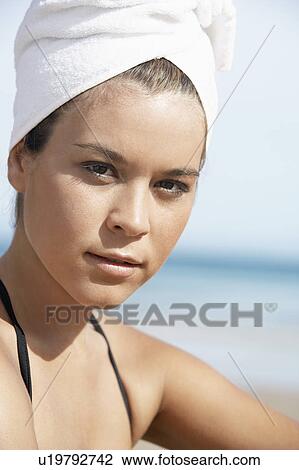 Stock Image - Young woman with hair wrapped in towel on beach, close-up. Fotosearch