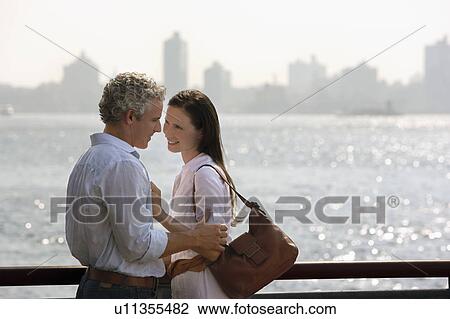 Stock Image - Affectionate couple embracing by river. Fotosearch