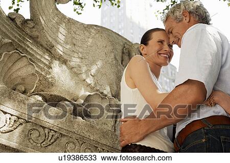 Affectionate couple embracing outdoors, low angle view View Large Photo Image Stock Image - Affectionate couple embracing outdoors, low angle view. Fotosearch