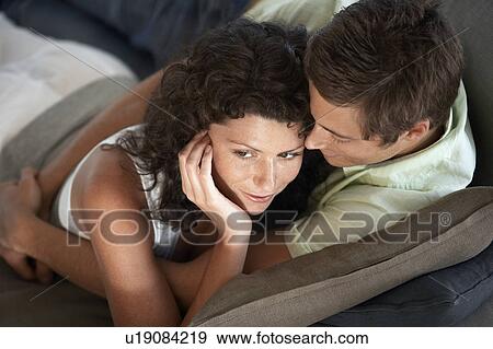 Affectionate couple lying on couch indoors, elevated view View Large Photo Image Stock Photo - Affectionate couple lying on couch indoors, elevated view. Fotosearch