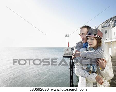 Affectionate couple, standing on pier, looking out to sea View Large Photo Image Stock Image - Affectionate couple, standing on pier, looking out to sea. Fotosearch