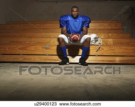American football player sitting on bench holding ball, portrait View Large Photo Image Stock Image - American football player sitting on bench holding ball, portrait. Fotosearch