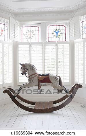 Picture - Antique rocking horse in bay window with stained glass, London. Fotosearch