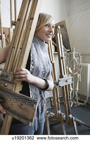 Stock Image - Art student carrying easel into studio. Fotosearch