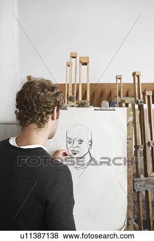 Stock Photo - Artist drawing charcoal portrait in studio, back view. Fotosearch