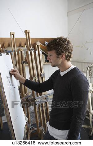 Stock Photograph - Artist drawing charcoal portrait in studio, side view. Fotosearch